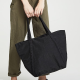 woman in olive jumpsuit holds black fabric tote bag