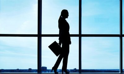 professional woman wears stylish suit; she is silhouette against a window