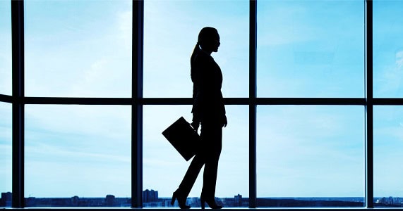 professional woman wears stylish suit; she is silhouette against a window