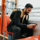 A man on a train looking at his phone and smiling
