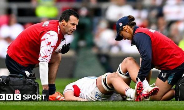 Morwenna Talling and Natasha Hunt on the pitch on crutches
