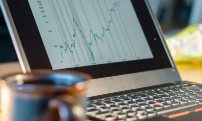 Laptop screen shows rising financial chart