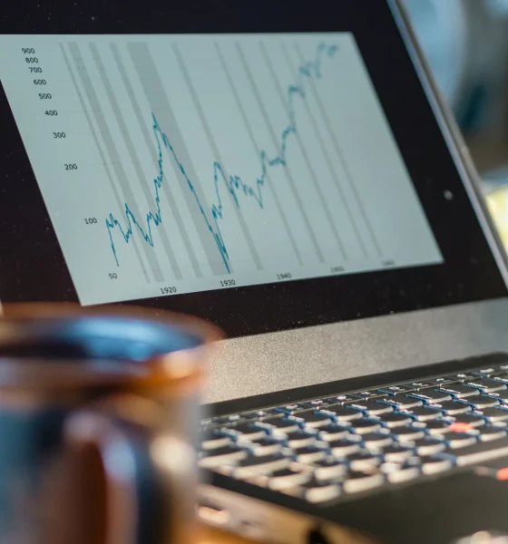 Laptop screen shows rising financial chart