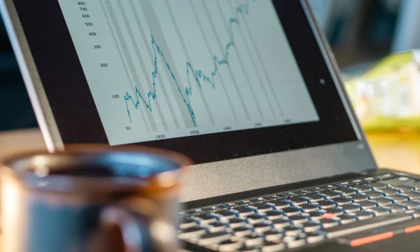 Laptop screen shows rising financial chart