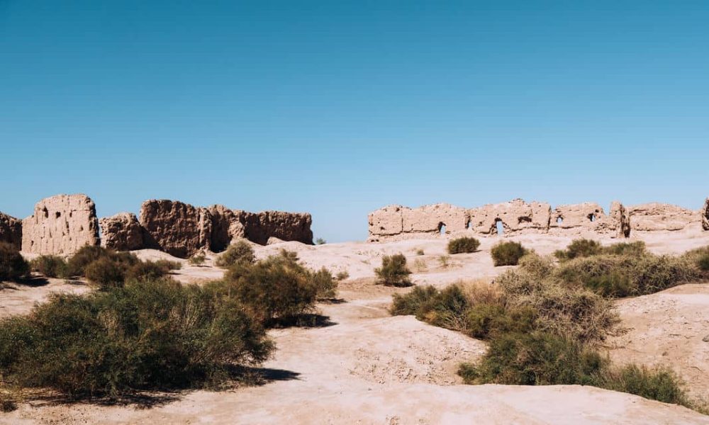 Ancient ruins on a dry, sandy landscape under a clear blue sky.