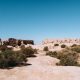 Ancient ruins on a dry, sandy landscape under a clear blue sky.