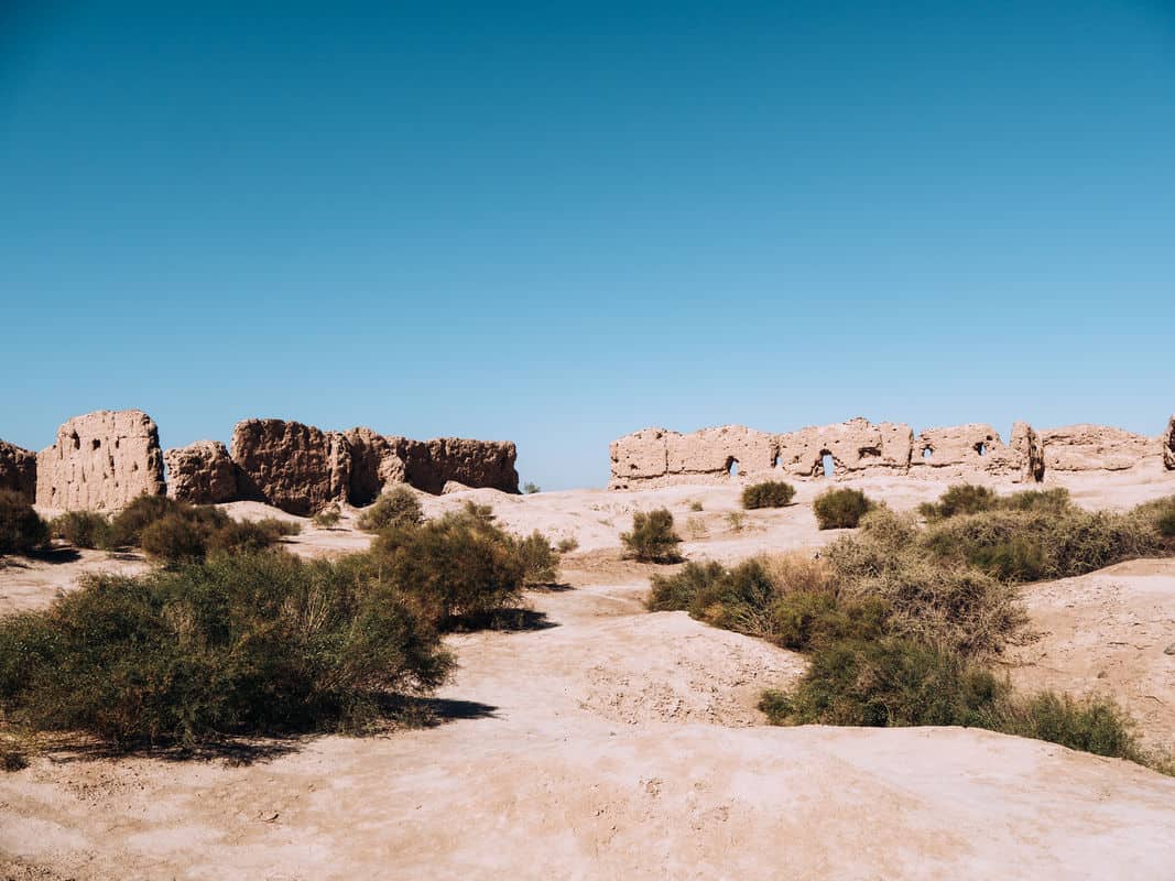 Ancient ruins on a dry, sandy landscape under a clear blue sky.