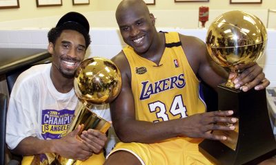 Kobe Bryant (L) of the Los Angeles Lakers holds the Larry O'Brian trophy as teammate Shaquille O'Neal (L) hold the MVP trophy after winning the NBA Championship against Indiana Pacers 19 June, 2000