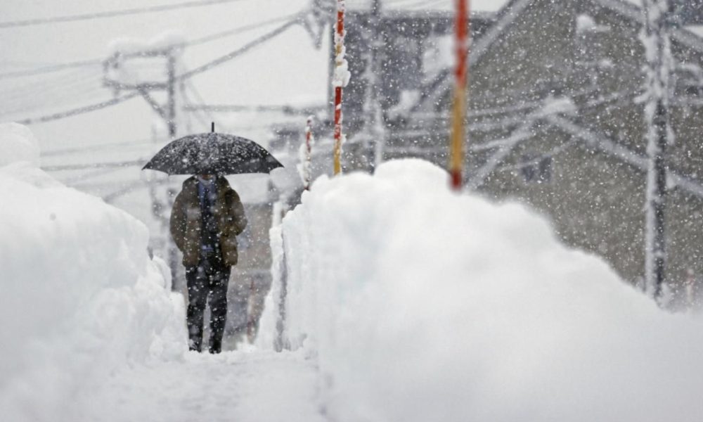 A man walks in heavy snow in Uonuma, Niigata Prefecture, on Dec. 20, 2022.