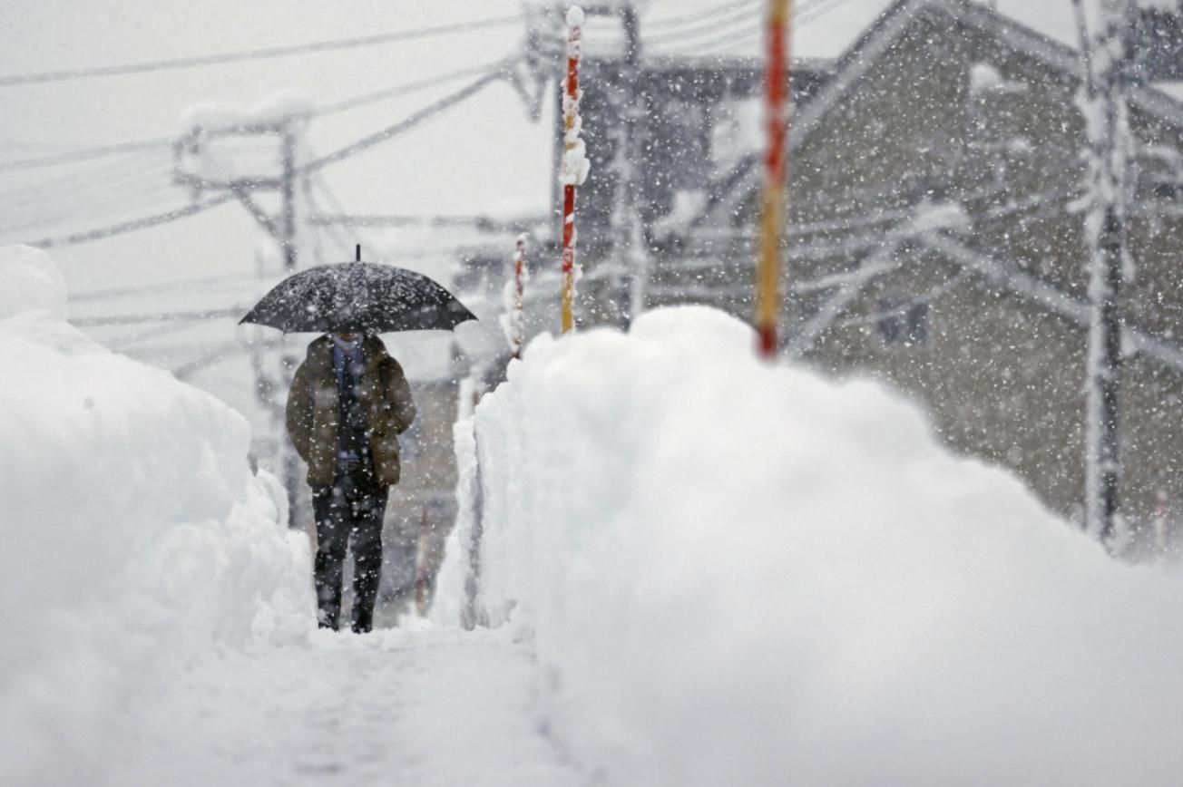 A man walks in heavy snow in Uonuma, Niigata Prefecture, on Dec. 20, 2022.