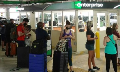 People wait in line at an Enterprise rental agency at Miami International Airport in April 2021