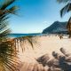 Playa de Las Teresitas beach in Tenerife with golden sand, palm trees, and mountains under a clear summer sky