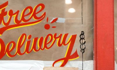 store window has hand painted (?) sign that says "free delivery"