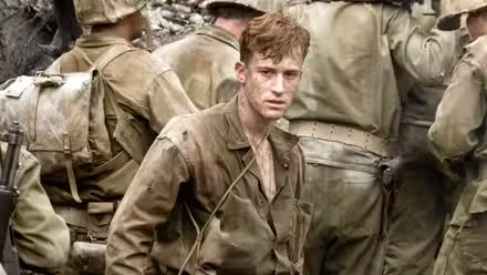 A young soldier faces the camera among a crowd of other turned-away soldiers in The Pacific.