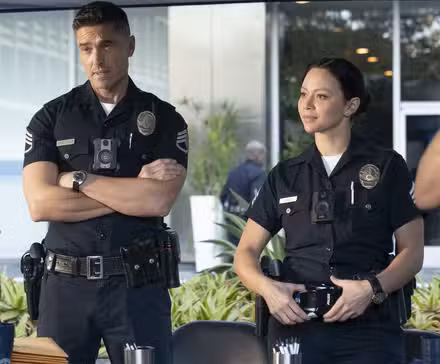 Tim Bradford and Lucy Chen, in uniform, at a recruitment booth in Season 8, Episode 13 of 'The Rookie'