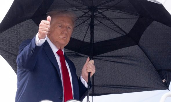 US President Donald Trump holds an umbrella as gives a thumbs up while boarding Air Force One prior to departure from Joint Base Andrews in Maryland, October 12, 2025