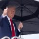 US President Donald Trump holds an umbrella as gives a thumbs up while boarding Air Force One prior to departure from Joint Base Andrews in Maryland, October 12, 2025