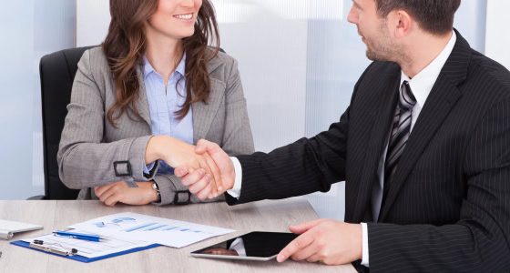 young professional woman (possibly a summer associate or law firm intern) shaking hands with an older man in a suit