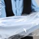 dry cleaning professional holds out a blue shirt wrapped in plastic