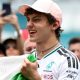 Kimi Antonelli celebrates his race win in Miami while holding the Italian flag. A crowd are gathered around him and taking photographs