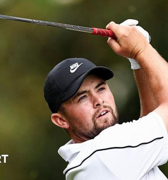 Alex Fitzpatrick watches his ball after playing an iron shot, with the club above his head