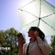 Two women wearing sunglasses on a sunny day. One carrying an umbrella and mobile phone