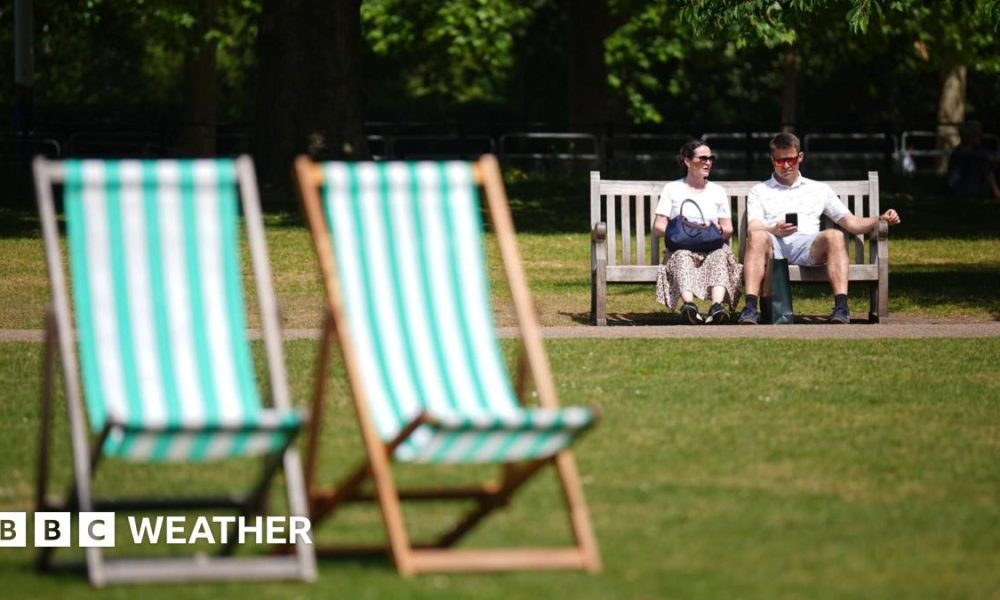 A man and a woman sitting on a bench in a London park on the hottest day of the year so far