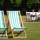 A man and a woman sitting on a bench in a London park on the hottest day of the year so far