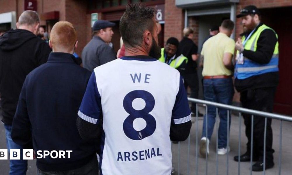 A Tottenham fan wearing shirt saying 'We 8 Arsenal'