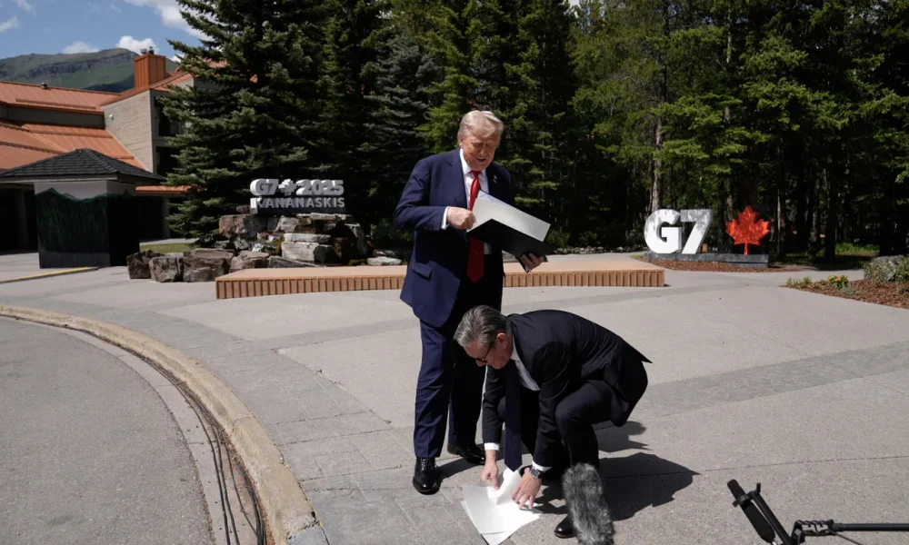 Starmer picks up the UK-US trade agreement papers dropped by Trump before speaking to the media at the G7 summit in Kananaskis, Alberta, Monday June 16, 2025.