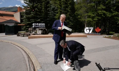 Starmer picks up the UK-US trade agreement papers dropped by Trump before speaking to the media at the G7 summit in Kananaskis, Alberta, Monday June 16, 2025.