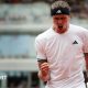 Alexander Zverev, wearing a white t-shirt and black headband, roars with his mouth wide open and clenches his right fist in celebration