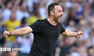Roberto de Zerbi celebrates with a broad smile and arms outstretched as he runs on to the pitch in a black T-shirt