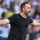Roberto de Zerbi celebrates with a broad smile and arms outstretched as he runs on to the pitch in a black T-shirt