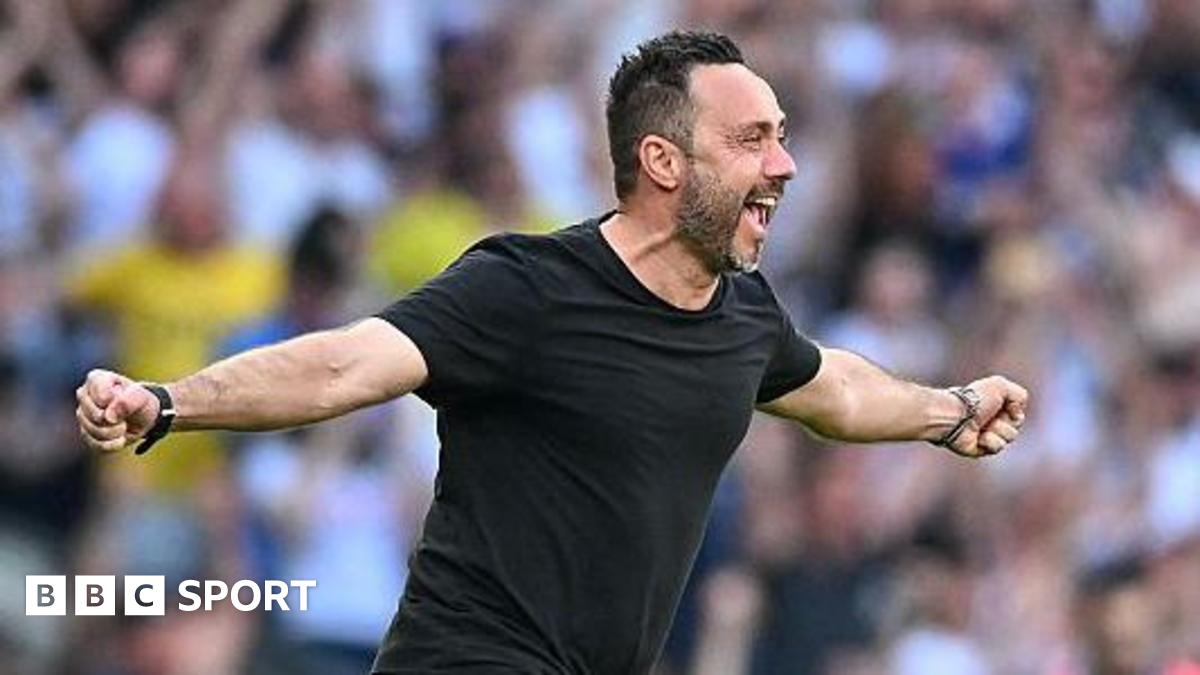 Roberto de Zerbi celebrates with a broad smile and arms outstretched as he runs on to the pitch in a black T-shirt