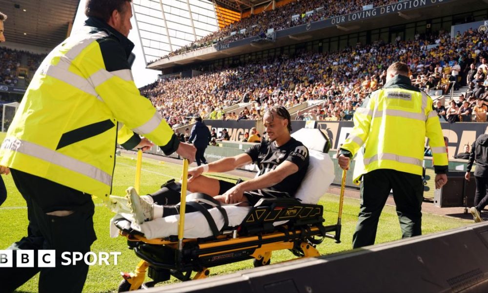 Xavi Simons being wheeled down a touchline on a stretcher