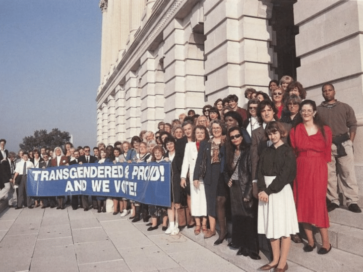 Archive photo of a line of people holding a banner that says 'Transgender and proud! And we vote'.