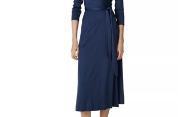 A woman wearing a dark blue midi dress and white slides