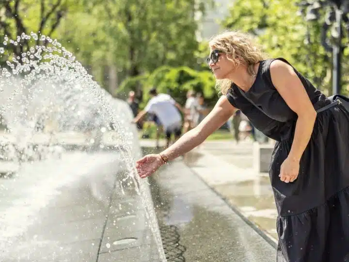 A woman cools down at a city centre cooling fountain Climate adaptation