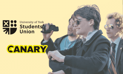 A picture of a Restore Britain Society fan holding a camera. On the left are both the University of York Student Union Logo and the Canary UK logo