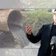 Andy Burnham in front of a sewage pipe