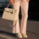 Shanice Messina is seen wearing a pink cropped marlene bouclé pants from Zara, a pink bouclé box jacket from Zara, a pair of leather moccasins in ivory with golden logo detail from Chanel, a white Kelly bag with golden details from Hermès, stacked rings with gemstones from Pomellato, a golden Just en Clou and LOVE bracelet from Cartier on May 11, 2025 in Munich, Germany.