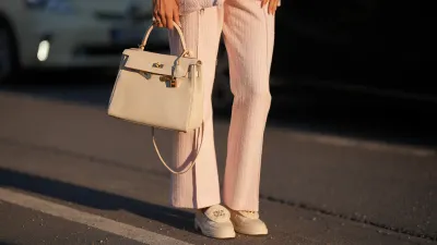 Shanice Messina is seen wearing a pink cropped marlene bouclé pants from Zara, a pink bouclé box jacket from Zara, a pair of leather moccasins in ivory with golden logo detail from Chanel, a white Kelly bag with golden details from Hermès, stacked rings with gemstones from Pomellato, a golden Just en Clou and LOVE bracelet from Cartier on May 11, 2025 in Munich, Germany.