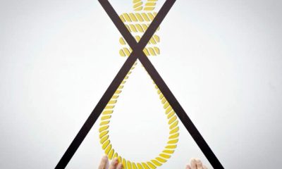 A protester against Israel's death penalty law holds a placard showing a noose crossed out