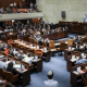 A view of the Knesset in Israel with people sat on the pew-type chairs inside with only the backs of their bodies visible