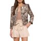 A woman wearing a tapestry blazer, light brown top, and cream-colored shorts with a bow