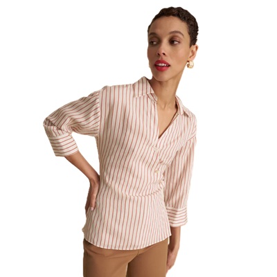 A woman wearing brown pants with a ivory-and-orange striped blouse