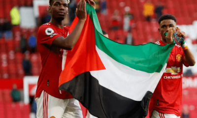 Manchester United's Paul Pogba (left) and Amad Diallo (right) applaud fans while holding a Palestinian flag in May 2021