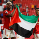 Manchester United's Paul Pogba (left) and Amad Diallo (right) applaud fans while holding a Palestinian flag in May 2021