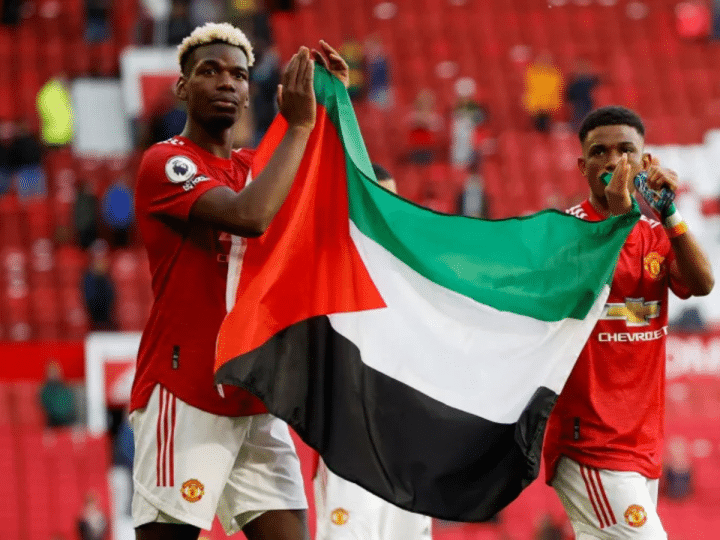 Manchester United's Paul Pogba (left) and Amad Diallo (right) applaud fans while holding a Palestinian flag in May 2021